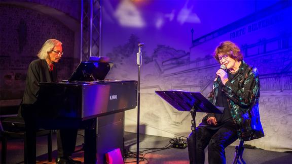 Brüning singt, König sitzt am Klavier.